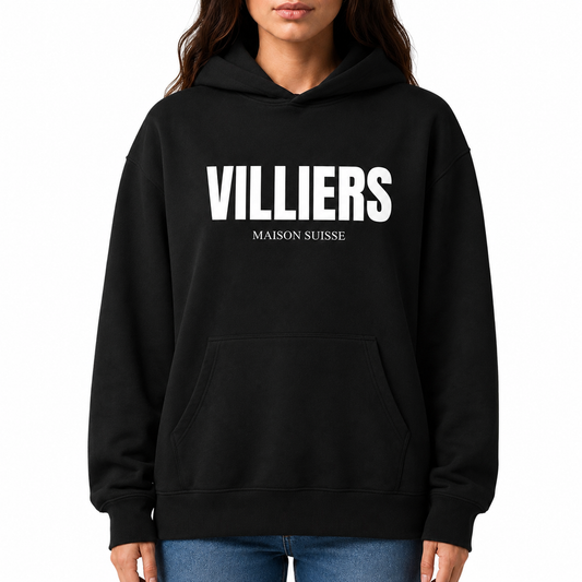 Damen Oversize Hoodie von VILLIERS MAISON SUISSE in Schwarz mit weißem Logo auf der Brust, getragen von einem Model in der Frontansicht.